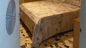Een slaapkamer met een bed, een aan de muur hangend kunstwerk, een deur met een reliëf en een kamer met een patroon op de vloer.