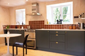 Une cuisine équipée d’une cuisinière, d’un four et d’une fenêtre donnant sur un paysage verdoyant.