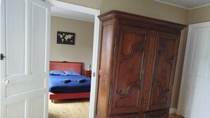 Ein Schlafzimmer mit einem Holzschrank, einem Bett mit blauer Bettwäsche und einer Weltkarte an der Wand.