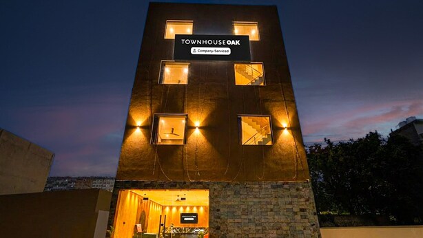 A modern building with a sign reading 'TOWNHOUSE OAK' and a company-serviced logo. - Super Deluxe Roomtroy Resorts and Wellness (Dera Bassi)
