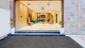 A hotel entrance with a stone facade, a wooden door, and a seating area inside. - Super Deluxe Roomtroy Resorts and Wellness (Dera Bassi)