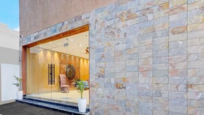 A modern building with a stone facade, a glass entrance, and a visible interior with a patterned wall and seating area. - Super Deluxe Roomtroy Resorts and Wellness (Dera Bassi)