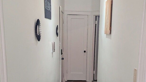 A hallway with a door at the end, a doormat, and wall decorations.