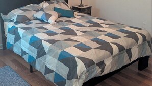 A bedroom with a bed, a nightstand, a lamp, and a wall painting.