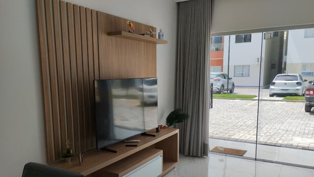 En moderne stue med et fladskærms-tv, væg med træpaneler og en skydedør, der fører til en parkeringsplads.