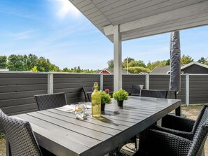 An outdoor patio with a wooden table, wicker chairs, and potted plants. - "Erikka" - 40km from the sea by Interhome (Ansager)
