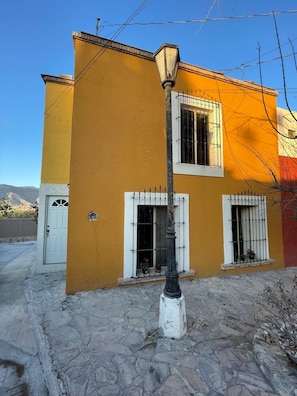 Un edificio amarillo con marcos de ventanas blancos, una puerta y una farola.