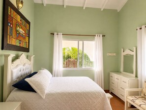 A bedroom with a bed, a dresser, a mirror, a window with curtains, and a painting on the wall. - Painted house- 4 pax, 4 min from the beach (Las Galeras)