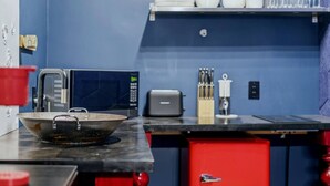 Una cocina con microondas, tostadora y un cajón rojo para guardar cosas.