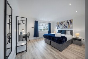 Ein modernes Schlafzimmer mit Bett, Nachttischen, Schreibtisch und Stuhl.