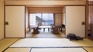 Une pièce de style japonais traditionnel, avec un sol recouvert de tatamis, une porte coulissante et une vue sur la mer.
