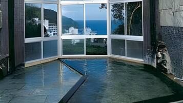 A corner room with large windows overlooking a body of water and a distant landscape.
