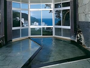 Een hoekzaal met grote ramen met uitzicht op een waterpartij en een ver landschap.