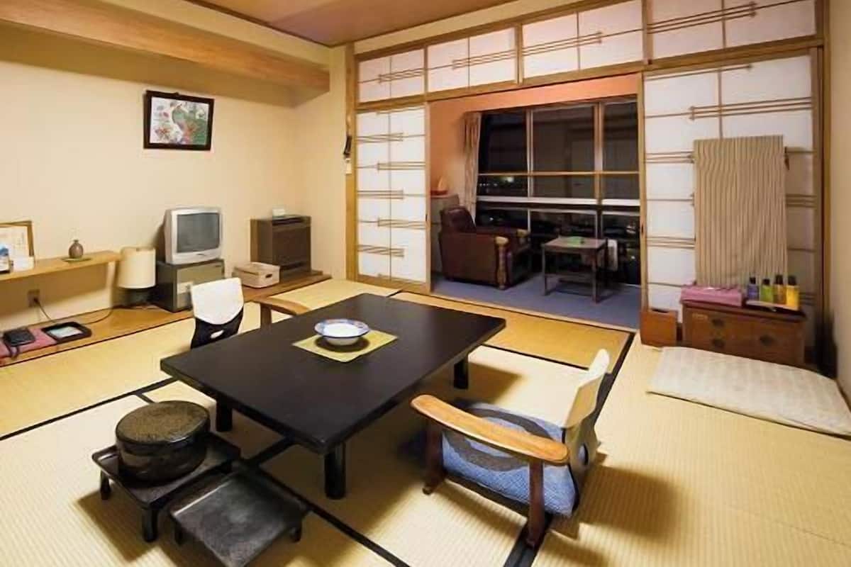 Een traditionele Japanse kamer met tatami vloerbedekking, een lage tafel, een bank en schuifdeuren.