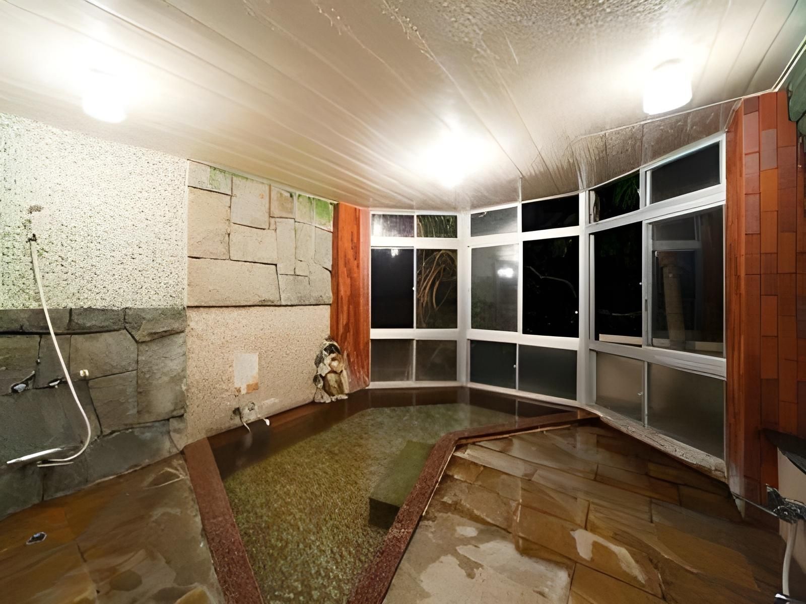 Ein Zimmer mit Steinwand, einer kleinen Statue und einem Fenster mit vielen Sprossen.