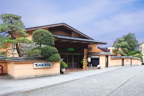 Ein traditionelles japanisches Gebäude mit einem Ziegeldach, einer Steinwand und Beschilderung.