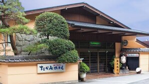 Un bâtiment de style architectural japonais traditionnel, caractérisé par un toit recouvert de tuiles et un mur en pierre.