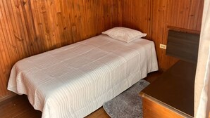 A single bed with a quilted white bedspread in a room with wooden panel walls. - Room-h6 Exceptional Location Near the Hi (Popayán)