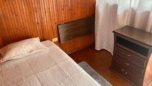 A wooden-paneled room with a bed, a dresser, and a radiator. - Room-h6 Exceptional Location Near the Hi (Popayán)