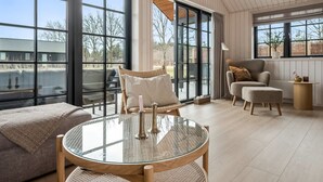 A spacious room with large windows, a round glass table, a sofa, and a chair. - "Emin" - 2.8km from the sea by Interhome (Henne)