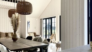 A room with a wooden table, chairs, a vase with dried flowers, and a wicker hanging light fixture. - "Emin" - 2.8km from the sea by Interhome (Henne)