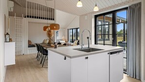 A modern kitchen with a central island, a dining area with a sofa, and large windows offering a view. - "Emin" - 2.8km from the sea by Interhome (Henne)