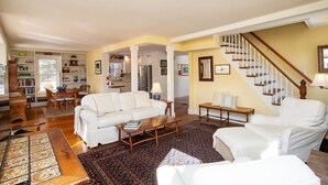 Ein großzügiges Wohnzimmer mit einer Couch, einem Couchtisch und einer Bank. Eine Treppe führt zu einer weiteren Ebene.