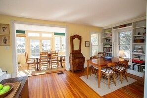 Un coin repas avec une table et des chaises en bois, un grand miroir et une bibliothèque remplie de livres.