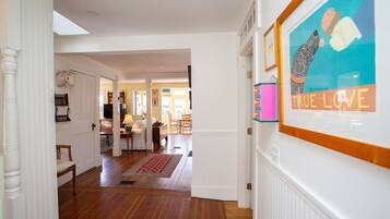 A hallway with wooden flooring, white walls, and a framed artwork on the wall.