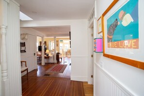 Un passadís amb sòl de fusta, parets blanques i una obra d'art emmarcada a la paret.