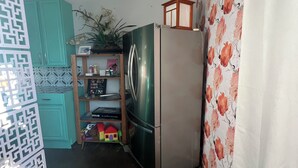 Una cucina compatta con frigorifero, pensili color petrolio, ripiano in legno e parete decorata.