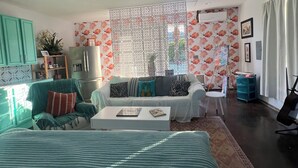 Una camera da letto con un letto, un ventilatore a soffitto, un divano, un tavolino da caffè e vista sull'esterno.