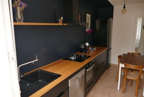 A kitchen with a wooden countertop, stainless steel appliances, a sink, and a dining area with a table and chairs.
