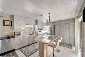 A modern kitchen with a central island, stainless steel appliances, and a dining area with a view. - Ripple Inn: private retreat mins to the Gulf (South Venice)