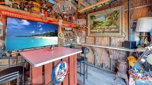 En bardel med en tv-skärm som visar en vy över en strand, träväggar och diverse dekorationer.