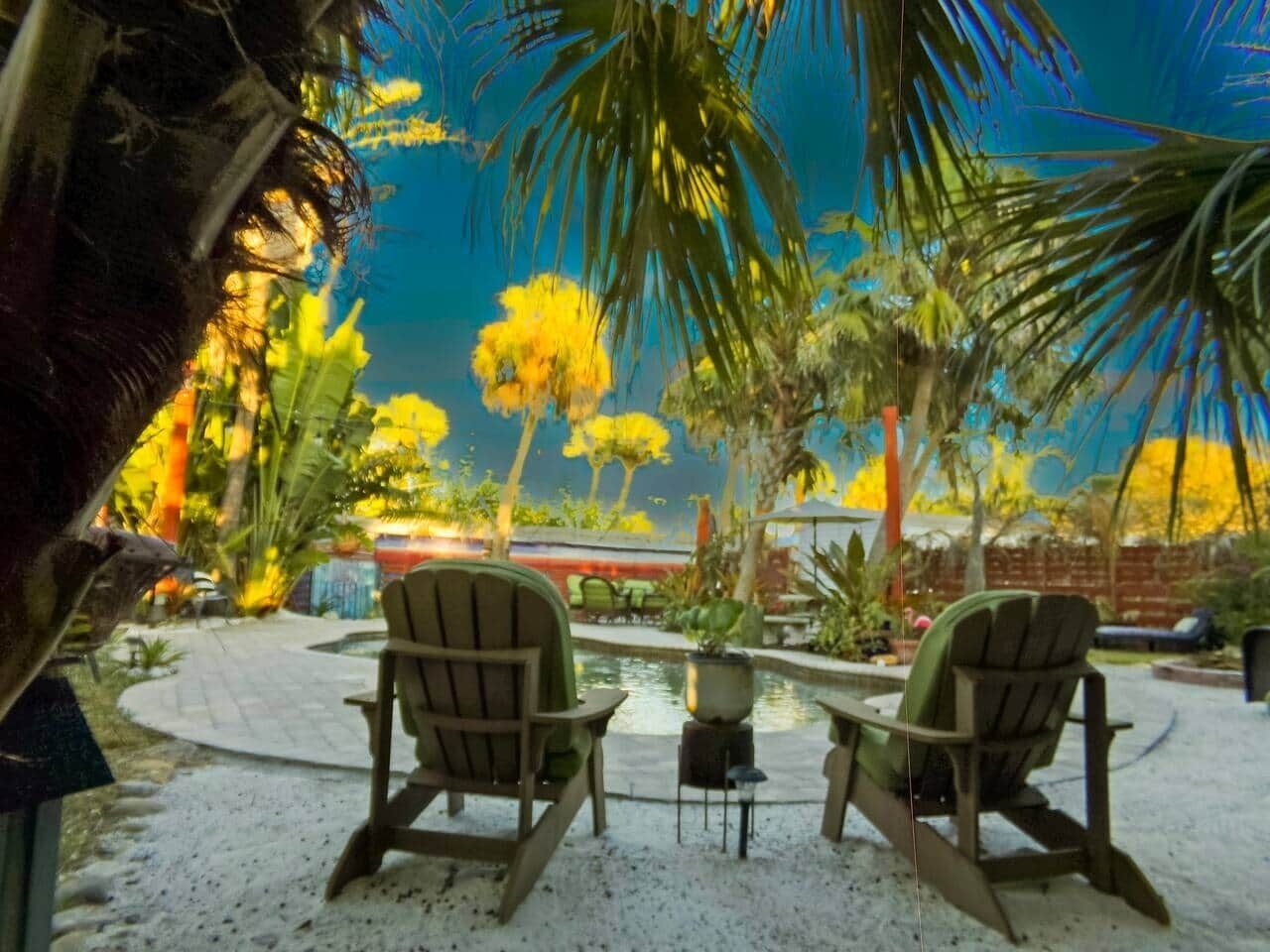Een terras met twee Adirondack-stoelen, een tafeltje en een zwembad.