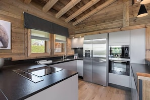 Eine moderne Küche mit Holzbalken, Edelstahlgeräten und einem großen Fenster.