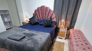 A bedroom with a bed, bedside tables, a nightstand, a bench, and a wardrobe. - Beautiful apartment overlooking medellin (Medellín)