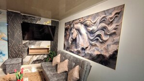 A modern living room with a sectional sofa, a flat-screen TV, and a large abstract painting. - Beautiful apartment overlooking medellin (Medellín)