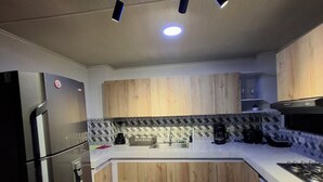A modern kitchen with wooden cabinets, a stainless steel refrigerator, a gas stove, and a patterned backsplash. - Beautiful apartment overlooking medellin (Medellín)