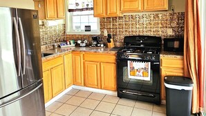 Una cocina con armarios de madera, un refrigerador de acero inoxidable, una estufa y un microondas.
