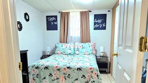 Un dormitorio con una cama, una mesita de noche, una lámpara y dos adornos en la pared.