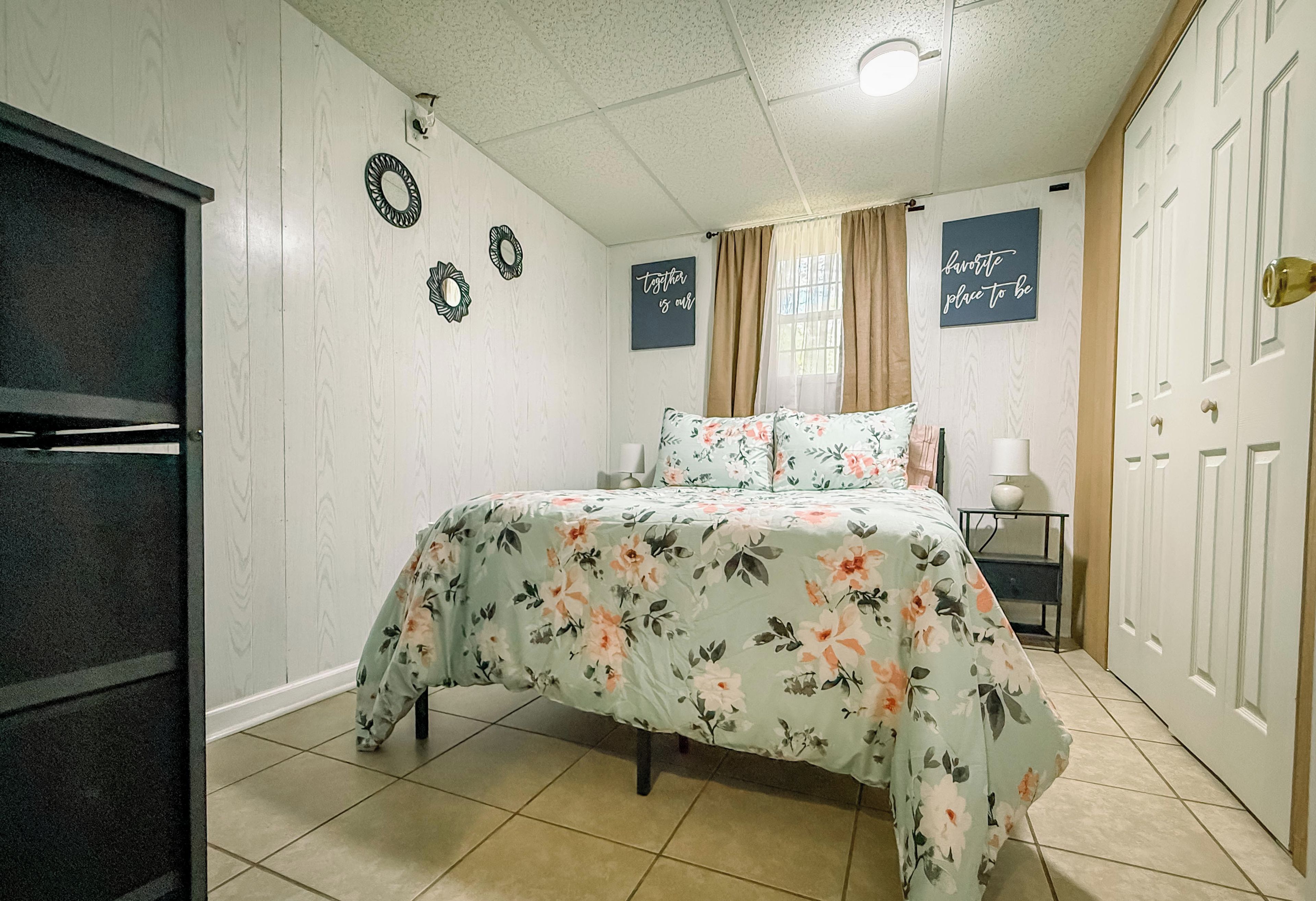 A bedroom with a bed, a wardrobe, a mirror, and a wall with decorative items.