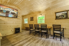 Een houten interieur met een open haard, een tafel met stoelen en een schilderij aan de muur.