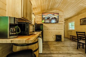 Un intérieur en bois comprenant un coin cuisine, un téléviseur diffusant l’émission « Serenity & Smokies », et une cheminée.