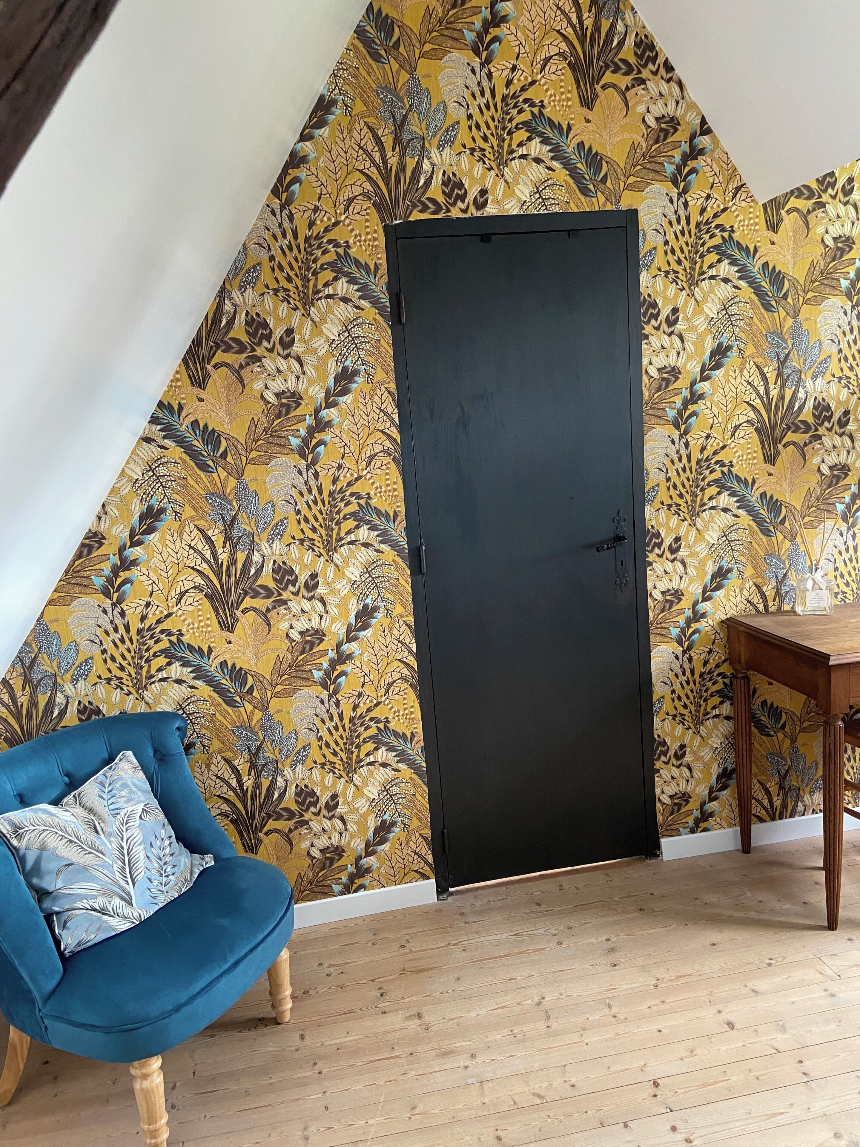 Ein Zimmer mit Holzboden, einer schwarzen Tür, einem blauen Stuhl und einem Tisch.