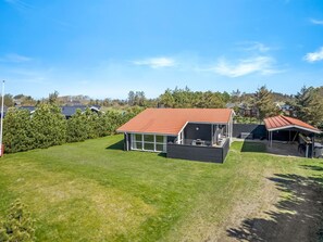 Ein modernes Haus mit rotem Dach, überdachter Terrasse und umzäunter Grundstück.