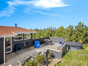 Une maison moderne dotée d’une terrasse, d’un espace salon extérieur et offrant une vue sur les arbres.