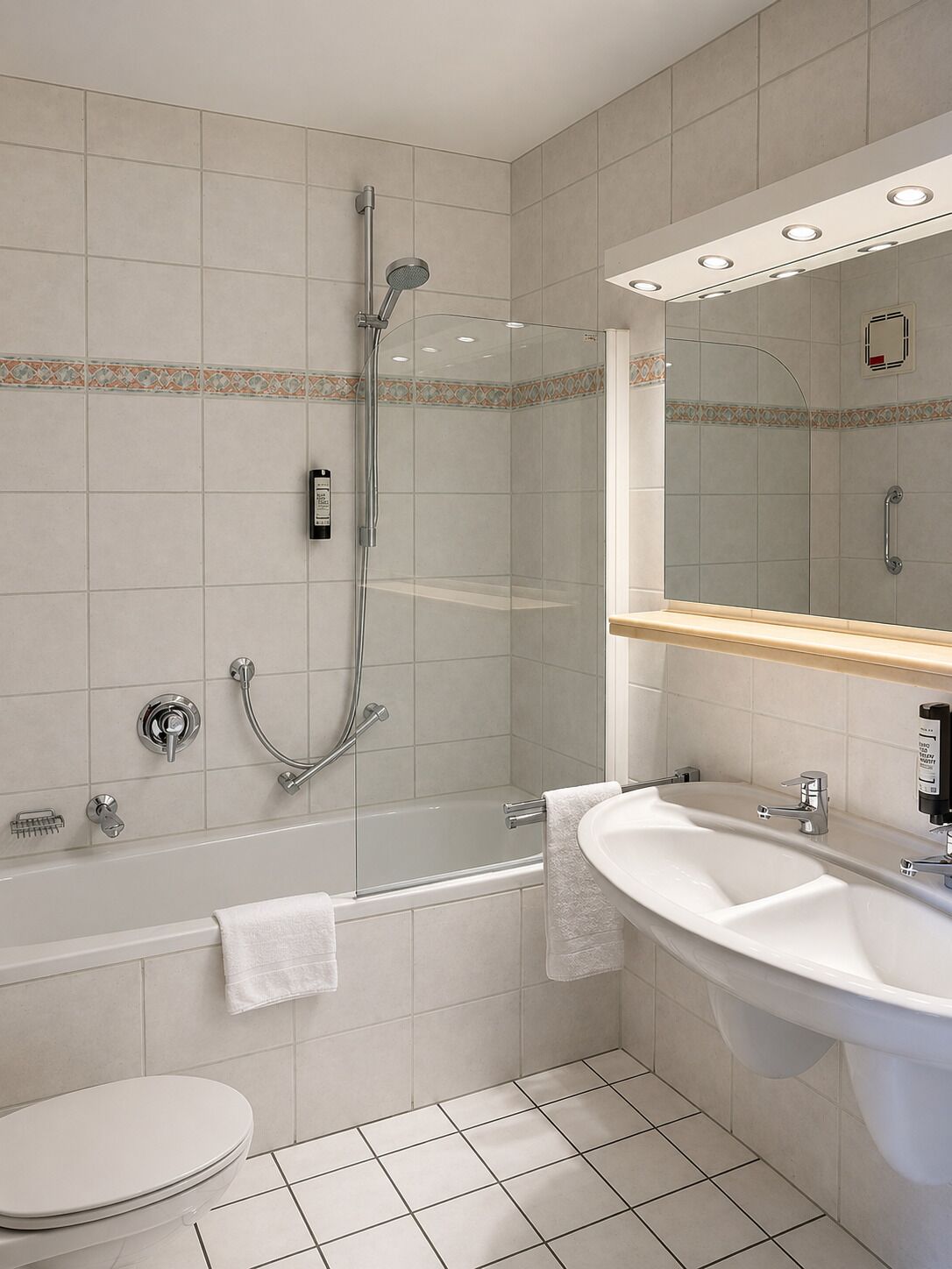 Un baño moderno con ducha envuelta en cristal, un lavabo blanco y un inodoro.