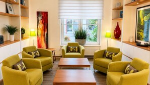 A modern living room with yellow sofas, a wooden coffee table, and a large window with blinds.